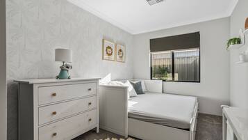 A bedroom with a bed, a dresser, a lamp, and two framed pictures on the wall.