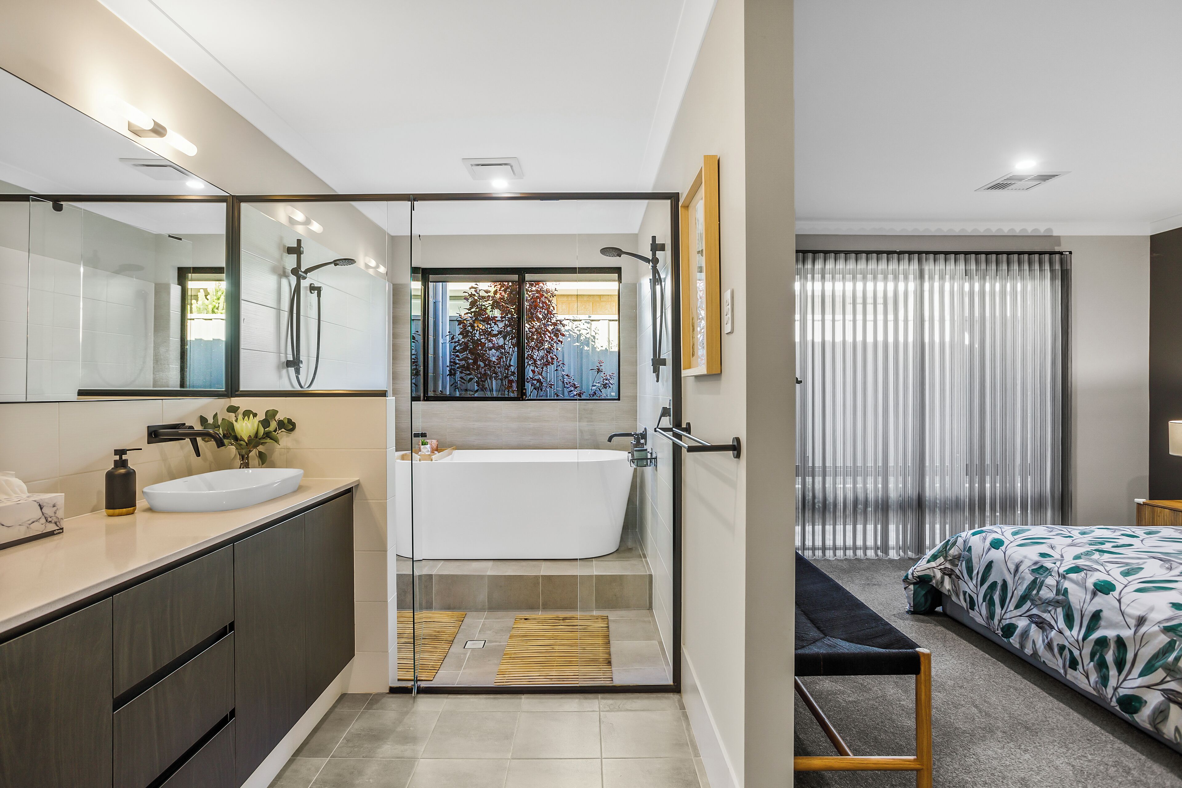 A modern bathroom with a glass-enclosed shower, a white bathtub, and a vanity with a sink.