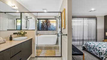 A modern bathroom with a glass-enclosed shower, a white bathtub, and a vanity with a sink.