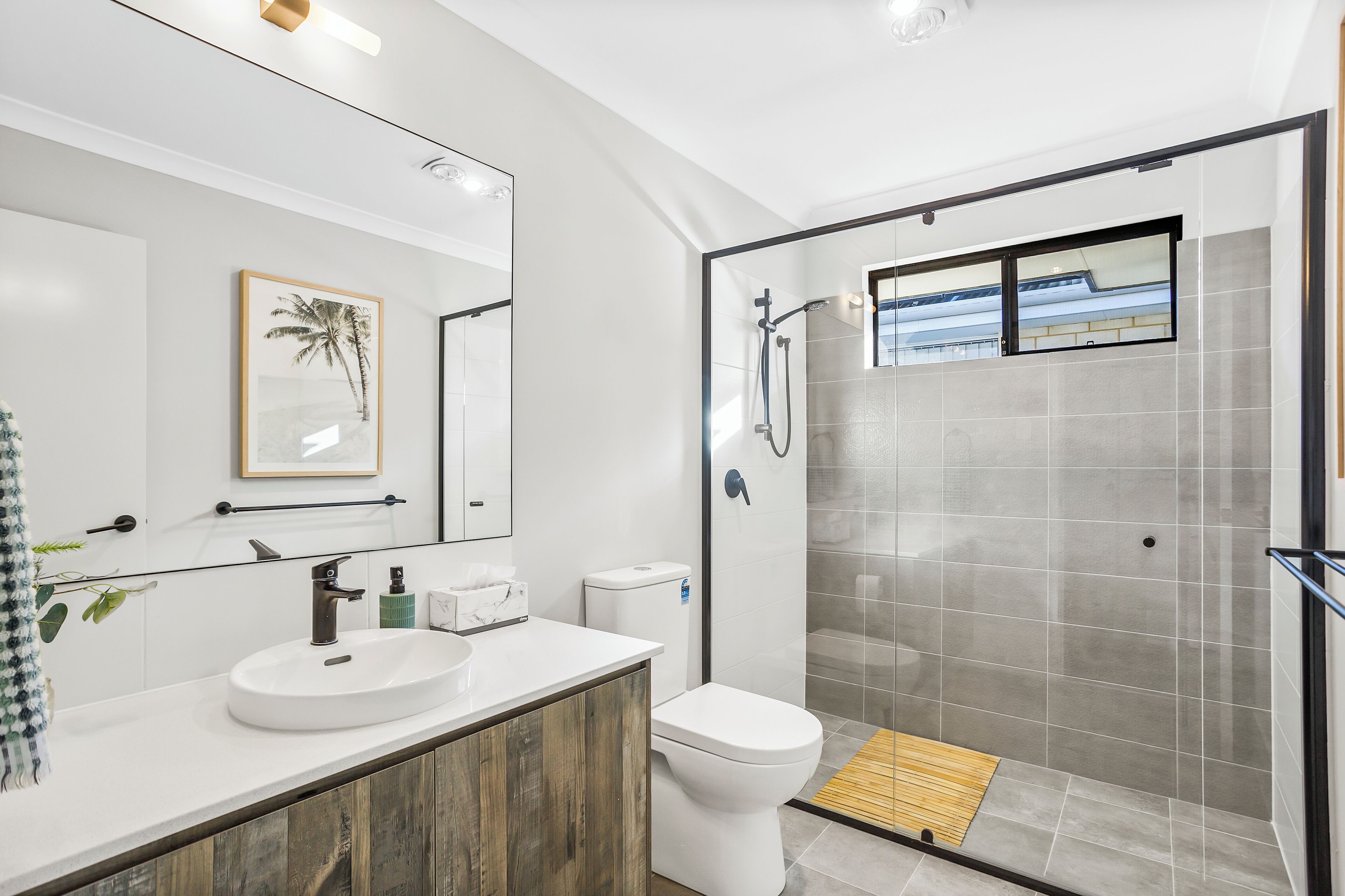 A modern bathroom with a white sink, toilet, and glass-enclosed shower.