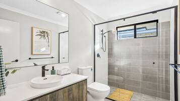 A modern bathroom with a white sink, toilet, and glass-enclosed shower.