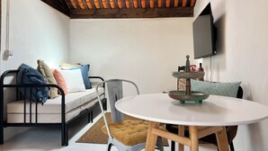 A compact living space with a bed, a small table, and a TV mounted on the wall. - Charming Little Home Terrace with wonderful ocean and mountain views. Fast Wi-Fi (Los Realejos)
