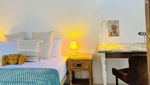 A cozy room with a bed, bedside lamp, and a desk with a chair. - Charming Little Home Terrace with wonderful ocean and mountain views. Fast Wi-Fi (Los Realejos)