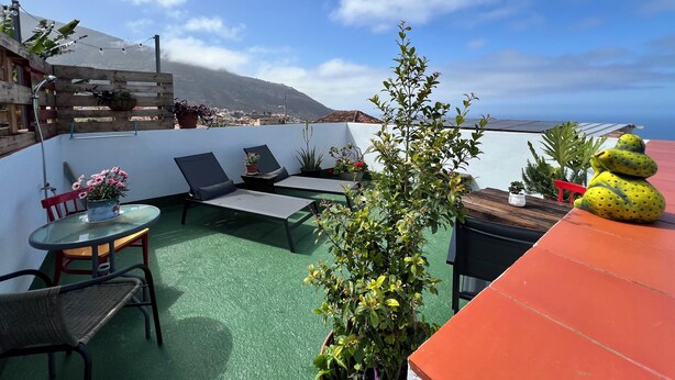 A rooftop terrace with a view of a mountain, a wooden fence, and potted plants. - Charming Little Home Terrace with wonderful ocean and mountain views. Fast Wi-Fi (Los Realejos)