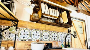 A kitchen with a wooden shelf holding plates and glasses, a pot on the counter, and a tiled backsplash. - Charming Little Home Terrace with wonderful ocean and mountain views. Fast Wi-Fi (Los Realejos)