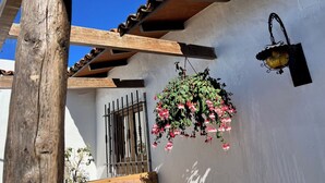 Una estructura de pérgola de madera, una cesta de flores colgante y un aplique de pared.