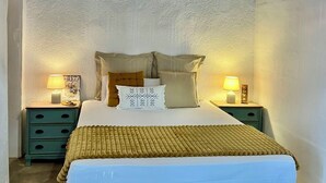 Un dormitorio con una cama, dos mesitas de noche, una lámpara y un aplique de pared.