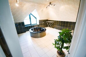 Een moderne badkamer met een vrijstaand bad, een raam en een potplant.