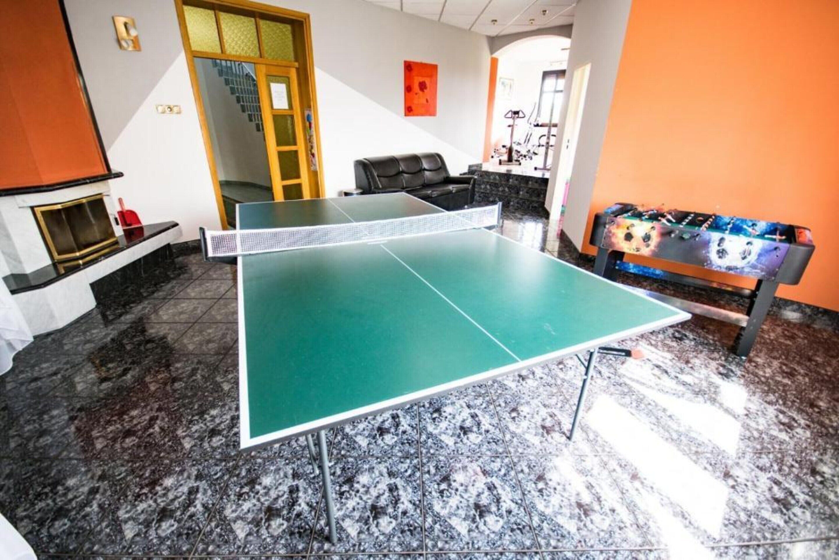 Ein Tischtennisch in einem Raum mit Kamin, einer Couch und einer farbenfrohen Bank.