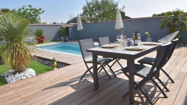 A wooden deck with a pool table and chairs, surrounded by potted plants and umbrellas. - House with swimming pool 300 metres from the beach and center (La Couarde-sur-Mer)