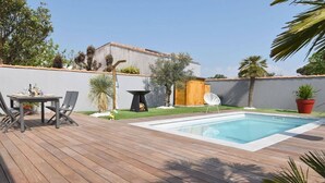 A wooden deck with a pool, a table with chairs, and a small garden area with plants and a wooden fence. - House with swimming pool 300 metres from the beach and center (La Couarde-sur-Mer)