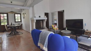 A spacious living room with a blue sofa, a fireplace, a television, and a dining area with a table and chairs. - House with swimming pool 300 metres from the beach and center (La Couarde-sur-Mer)