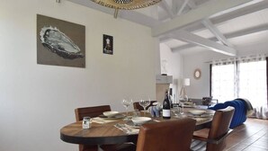 A dining area with a round table set for four, surrounded by leather chairs. There are wine glasses and a bottle on the table. - House with swimming pool 300 metres from the beach and center (La Couarde-sur-Mer)