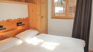 Een houten kamer met een bed, een raam en een gordijn.