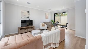 Un salon moderne doté d’un grand canapé, d’un téléviseur à écran plat et d’un coin repas avec des chaises et une table.