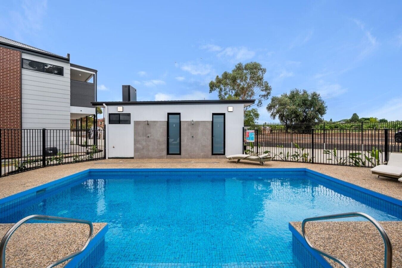 A swimming pool with a small building in the background, surrounded by a fence.