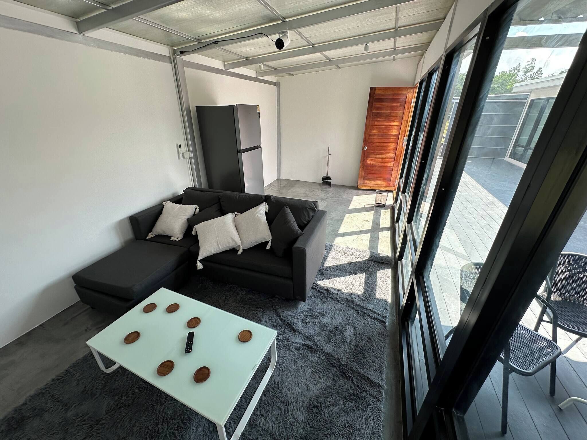 Uma sala de estar moderna com um sofá seccional, uma mesa de centro branca e uma janela grande com vista para o exterior.