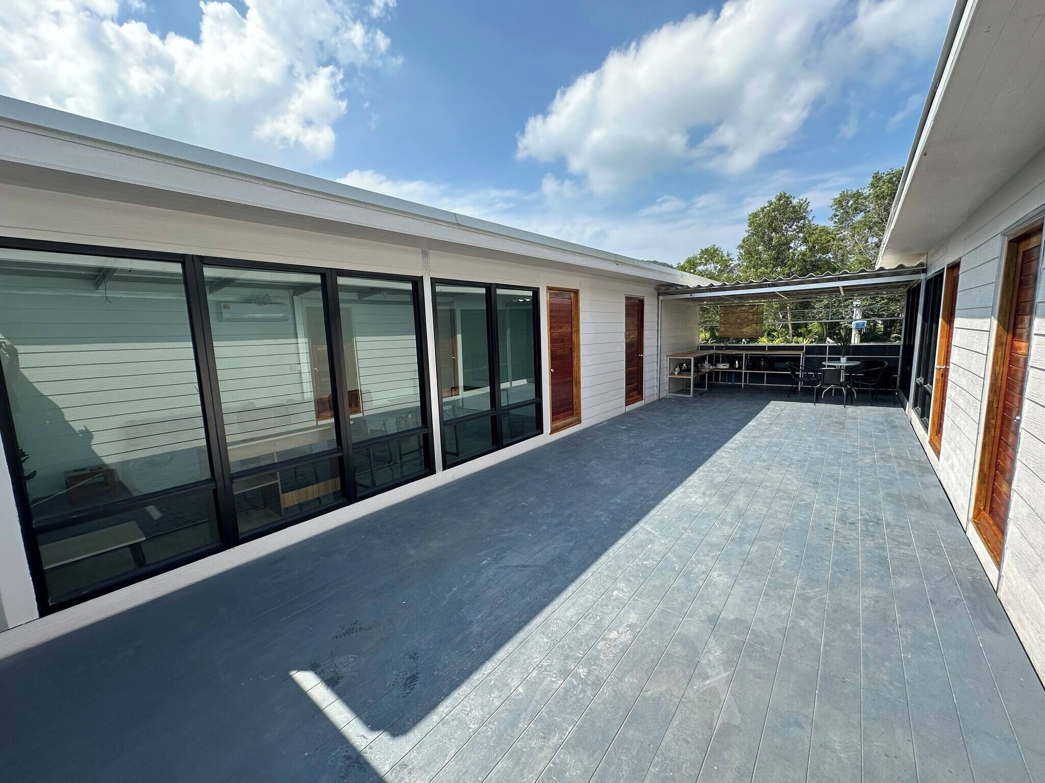 Een modern gebouw met grote glazen deuren, een overdekt terras en een plat dak.