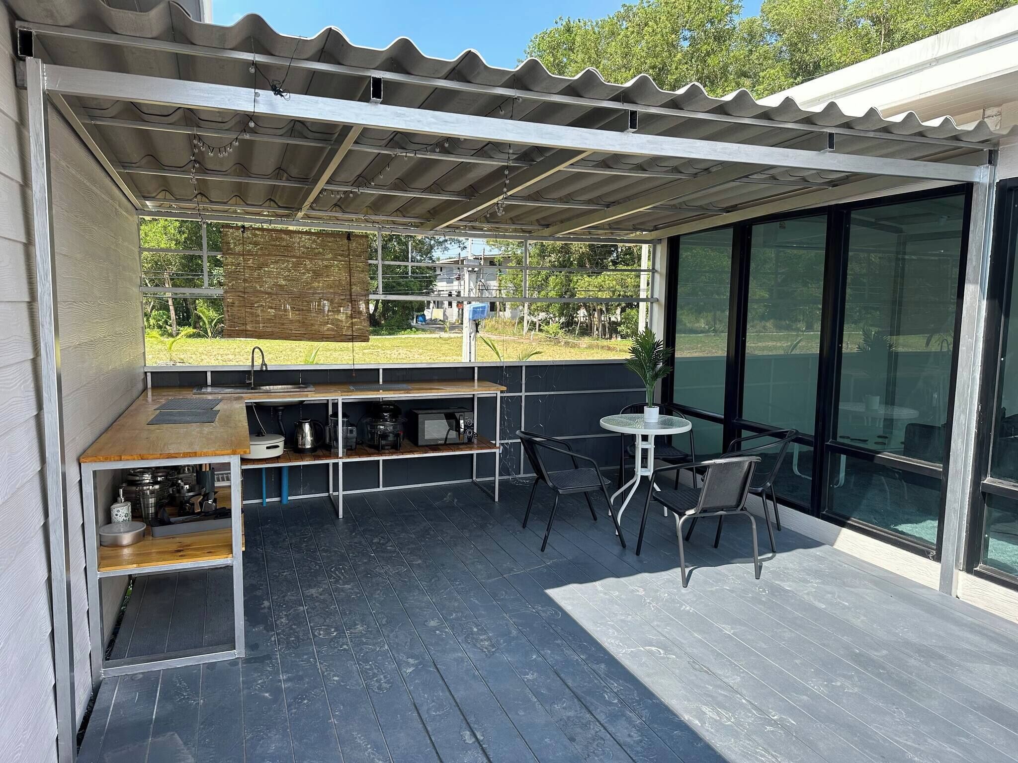 Een overdekte buitenruimte met een bar, stoelen en een kleine tafel.