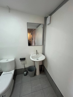 Un baño pequeño y limpio, con inodoro, lavamanos y espejo.
