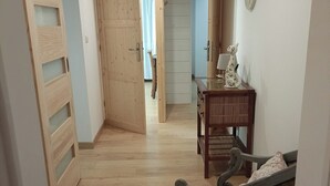 Un pasillo con suelo de madera, un banco, una mesa y una silla.