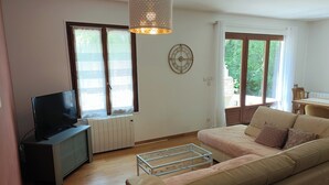 Una sala de estar con sofá, televisor, radiador y ventana con cortinas.
