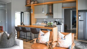 Een moderne keuken met een centraal eiland, barstoelen en een zithoek met een bank en stoelen.
