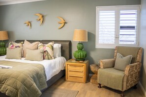 A bedroom with a bed, nightstands, a chair, and wall decorations.