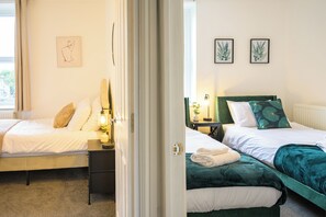 Een hotelkamer met twee bedden, een nachtkastje met een lamp en kunstwerken aan de muur.