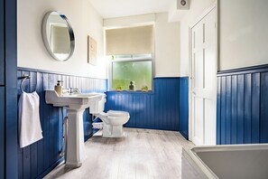 Een badkamer met een wit toilet, een witte wastafel en een spiegel.