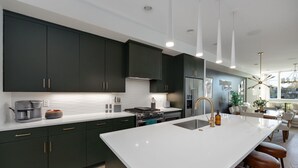 A modern kitchen with dark cabinets, a large island, and bar stools.