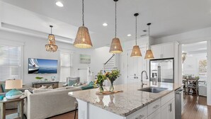 A modern kitchen with a central island, stainless steel appliances, and pendant lighting. - Pearl House: Luxury Retreat with Bikes and Golf Cart, and Pond & Nature Views, Pickleball Courts! (Santa Rosa Beach)