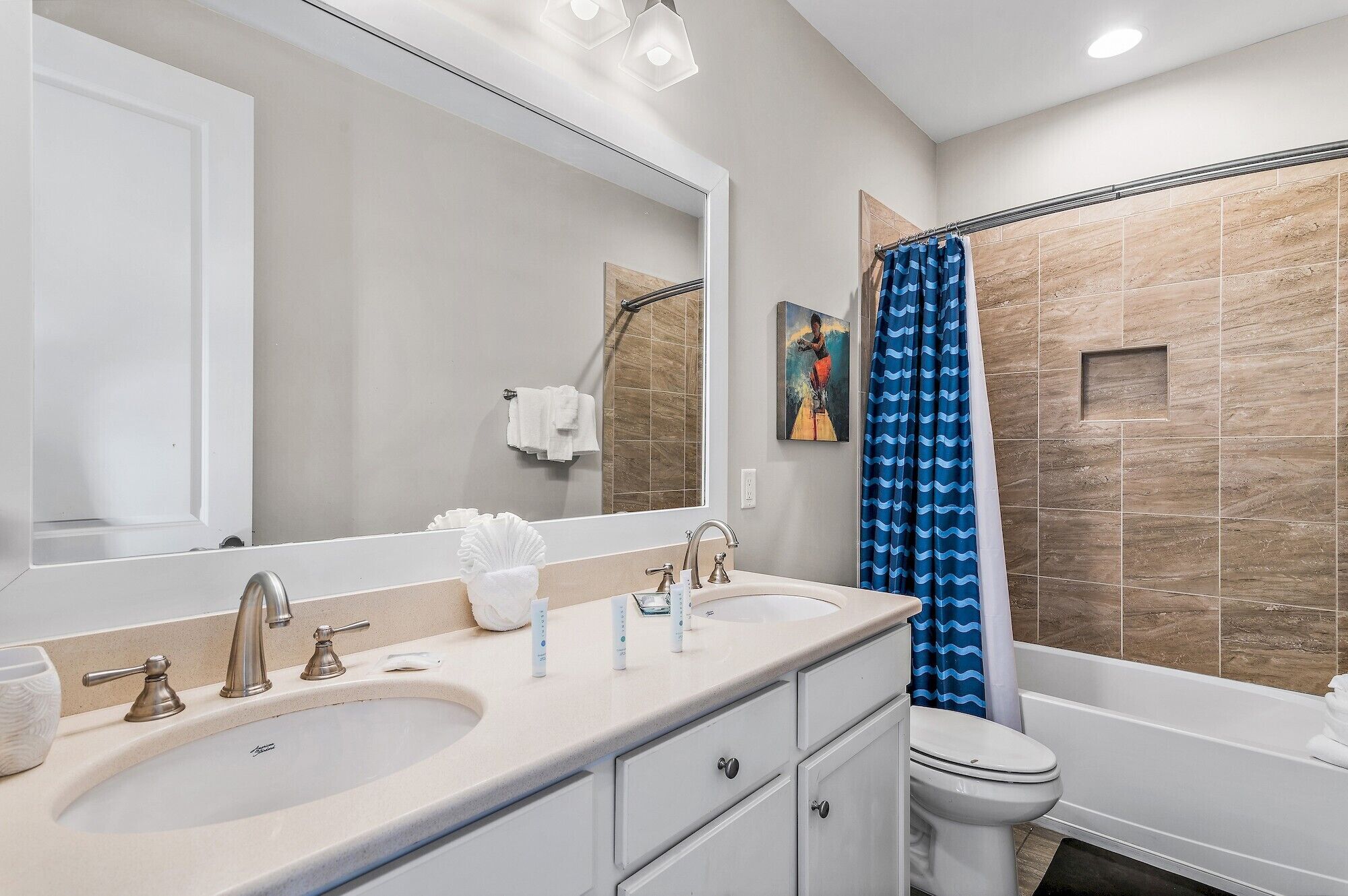 A bathroom with two sinks, a toilet, and a shower with a blue curtain.