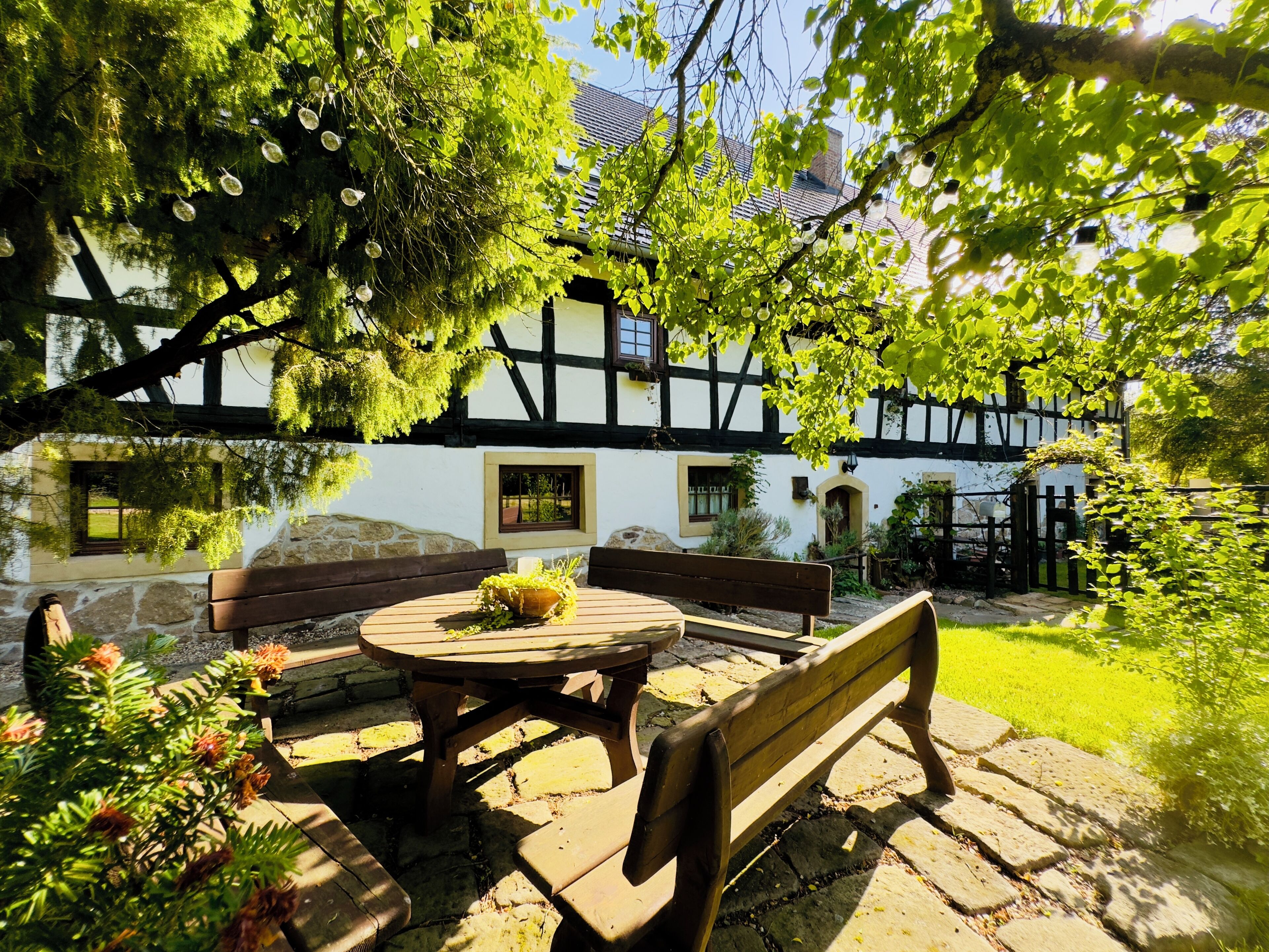 A traditional half-timbered house with a stone bench and a wooden table in the garden.
