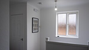 A hallway with a white door, a framed sign saying "GOOD VIBES ONLY", and a window with frosted glass. - 2-bedroom- Stoke-on-trent-sleeps 5-petsok (Stoke-on-Trent)