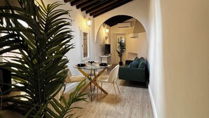 Et moderne interiør med et spisebord, en grøn sofa og en stor plante.