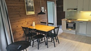 A compact kitchen with a wooden dining table and chairs, a built-in oven, and a sink. - Bergsgården Lodge Järvsö (Jarvso)