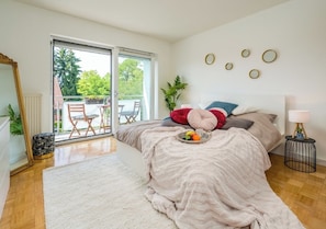 A bedroom with a bed, a window, a plant, and a small table with a tray.