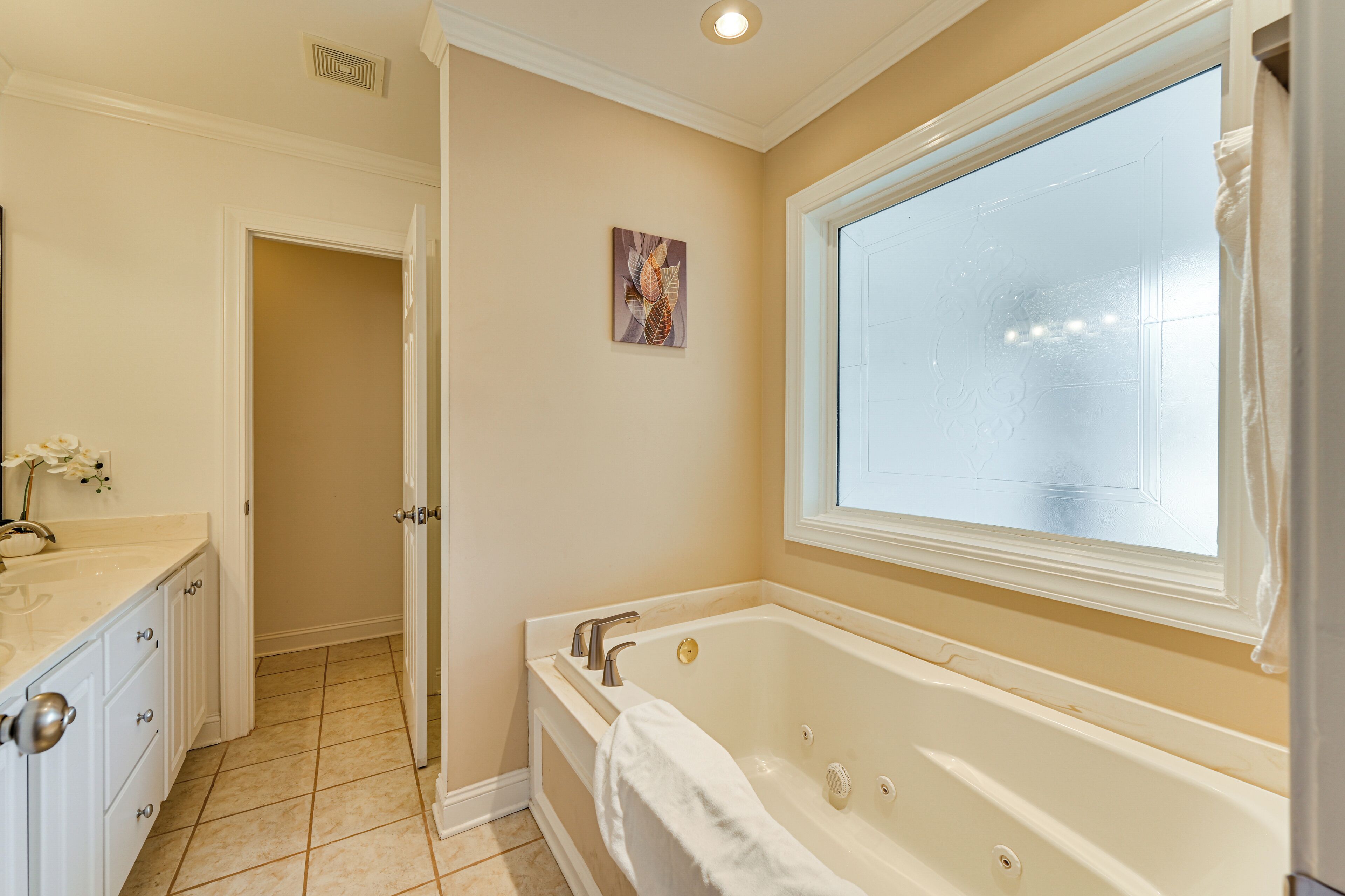 A bathroom with a bathtub, a window, a sink, and a door.