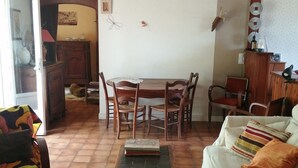 A cozy living room with a dining table, wooden chairs, a sofa, and a patterned rug. - Quiet house with garden Montignac Lascaux (Montignac-Lascaux)