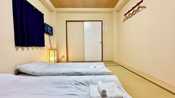 A hotel room with two beds, a television, a lamp, and a sliding door. - Along the airport line and 2 minutes from the nearest station, Japanese-style rooms with private bathrooms have excellent access [ 201]. (大阪市西成区花園北)
