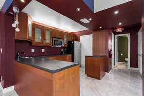 Une cuisine moderne avec des meubles en bois, un îlot central, des appareils électroménagers en acier inoxydable et un sol en marbre.