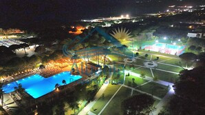 Vista aérea de un complejo turístico con piscina, jardines ajardinados y cancha de tenis.