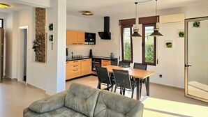 Una cocina moderna con armarios de madera, un comedor con mesa y sillas, y un sofá en la sala.