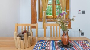 A dining area with a wooden table, chairs, a vase with flowers, and a patterned table runner. - Yeti Cabin (Plitvicka Jezera)