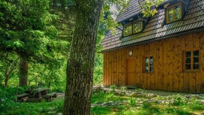 A wooden cabin with a stone pathway leading to the entrance, surrounded by lush greenery and trees. - Yeti Cabin (Plitvicka Jezera)