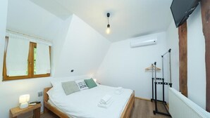 A bedroom with a bed, bedside table, lamp, and a hanging light fixture. - Yeti Cabin (Plitvicka Jezera)