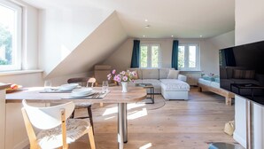 A modern loft apartment with a dining area, living room, and a loft bed. - Vogelkoje Living in nature, vacation apartment with terrace and beach chair (Rodenäs)