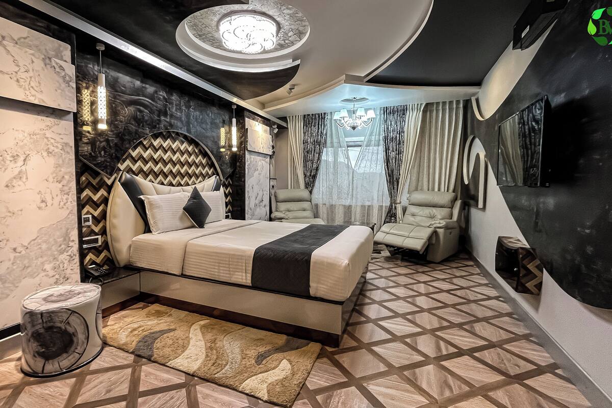 A modern bedroom with a bed, a chair, a rug, and a unique wall design.