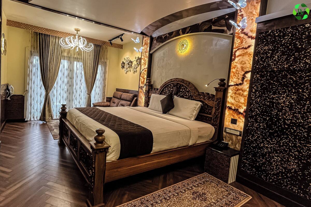 A spacious bedroom with a large bed, a chandelier, and a decorative wall.